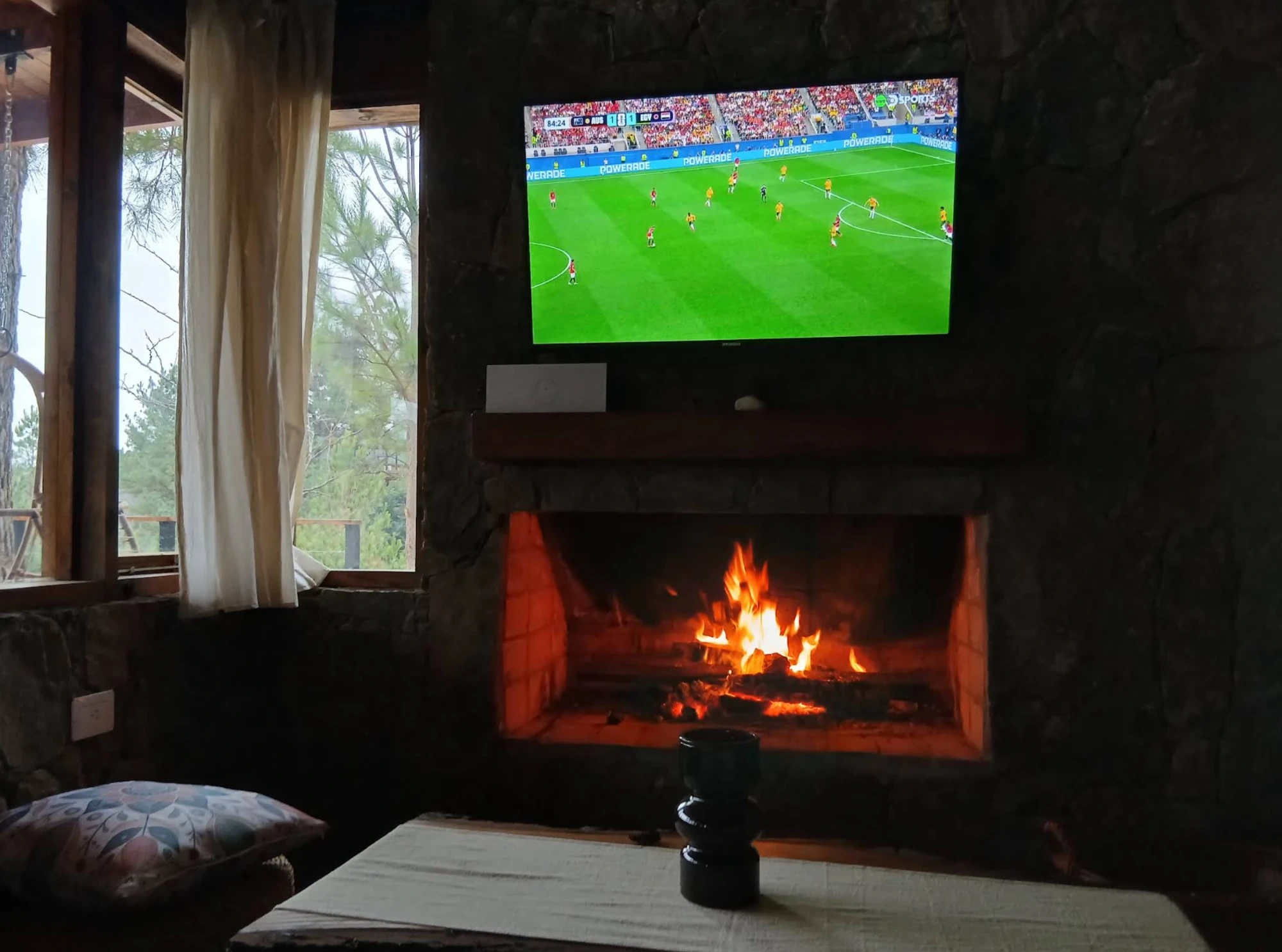 Estufa a leño de piedra con televisor en el living