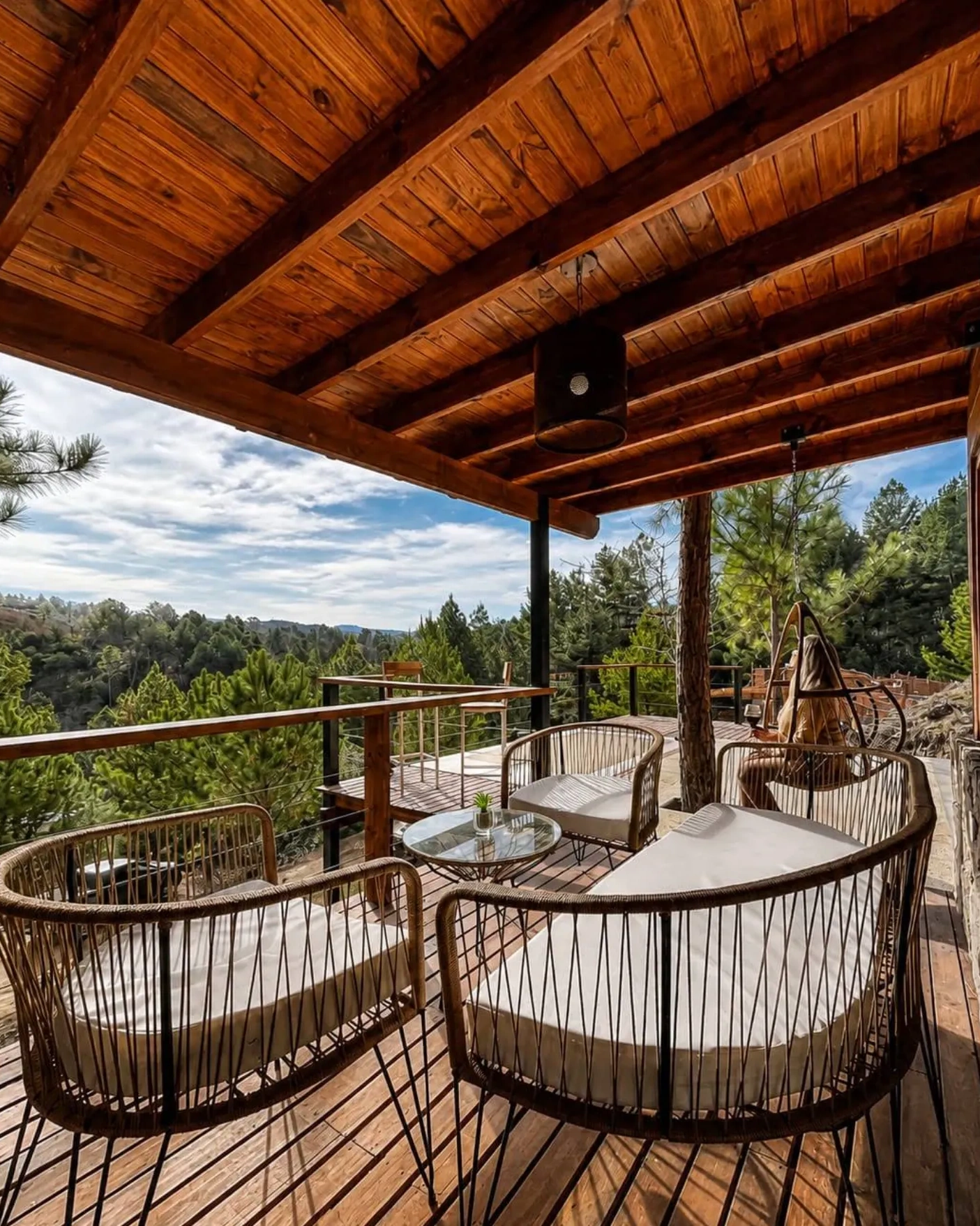 Deck cubierto con sillones de ratán y vista a las sierras y los pinos