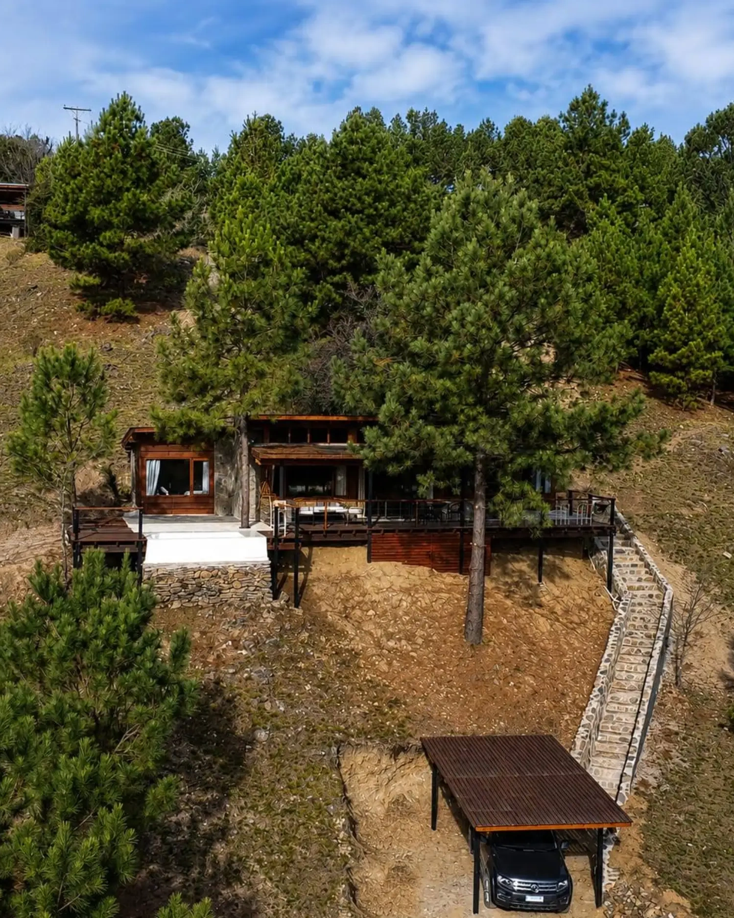 Vista aérea de Casa Malaika rodeada de pinos, con el deck y la cochera